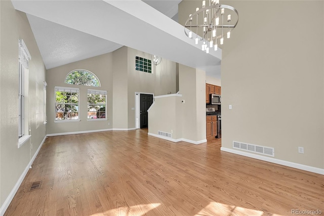 9008 W 101st Ave, Broomfield, CO 80021 - unfurnished living room with high vaulted ceiling, a chandelier, and light wood-type flooring