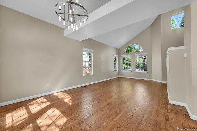 9008 W 101st Ave, Broomfield, CO 80021 - spare room featuring plenty of natural light, wood finished floors, high vaulted ceiling, and a chandelier