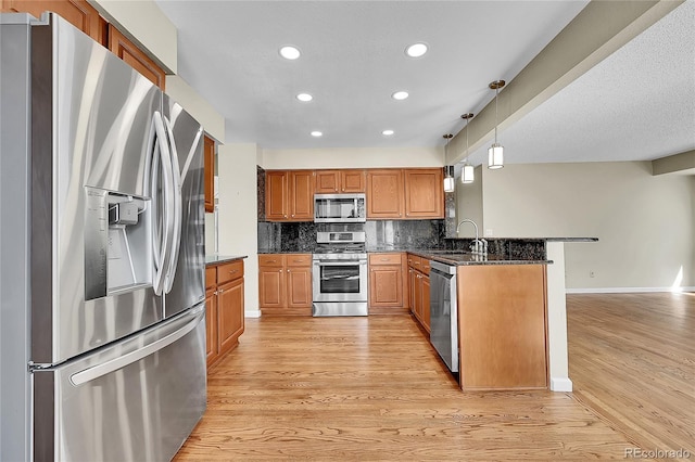 9008 W 101st Ave, Broomfield, CO 80021 - kitchen with appliances with stainless steel finishes, a peninsula, recessed lighting, light wood finished floors, and decorative backsplash