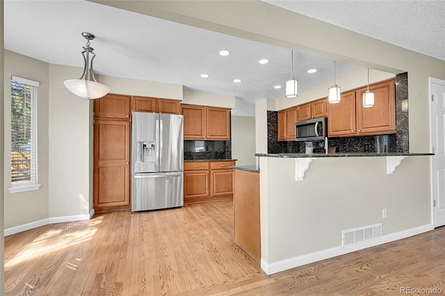 9008 W 101st Ave, Broomfield, CO 80021 - kitchen with stainless steel appliances, light wood-style flooring, backsplash, brown cabinets, and a kitchen breakfast bar