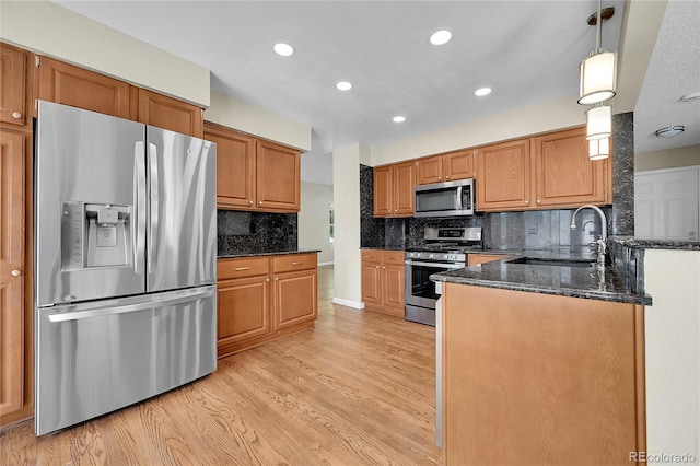 9008 W 101st Ave, Broomfield, CO 80021 - kitchen featuring appliances with stainless steel finishes, light wood finished floors, dark stone counters, decorative backsplash, and recessed lighting