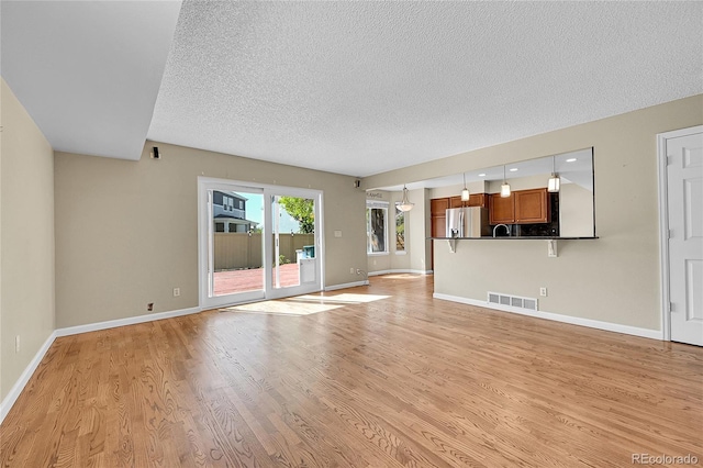 9008 W 101st Ave, Broomfield, CO 80021 - unfurnished living room with a textured ceiling and light wood-type flooring