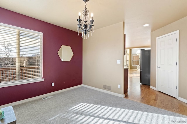 carpeted empty room with an inviting chandelier