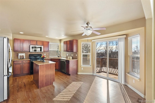 kitchen featuring tasteful backsplash, a center island, a healthy amount of sunlight, and appliances with stainless steel finishes