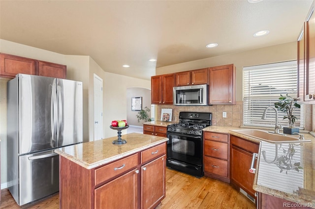 kitchen with sink, a center island, stainless steel appliances, backsplash, and light wood-type flooring