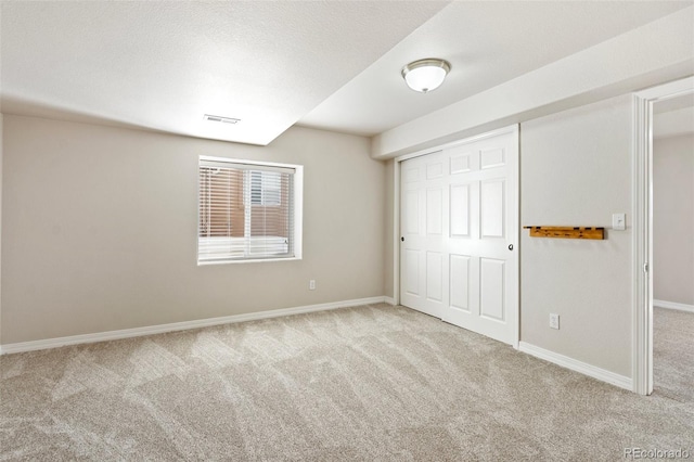 unfurnished bedroom with light colored carpet and a closet