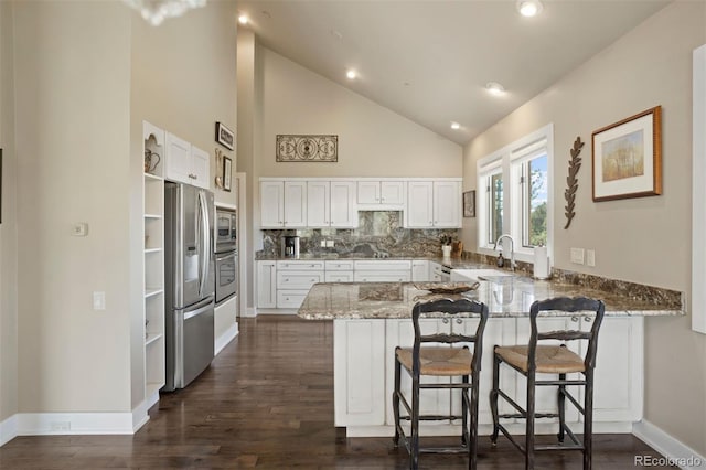 kitchen featuring appliances with stainless steel finishes, a breakfast bar, kitchen peninsula, and white cabinets