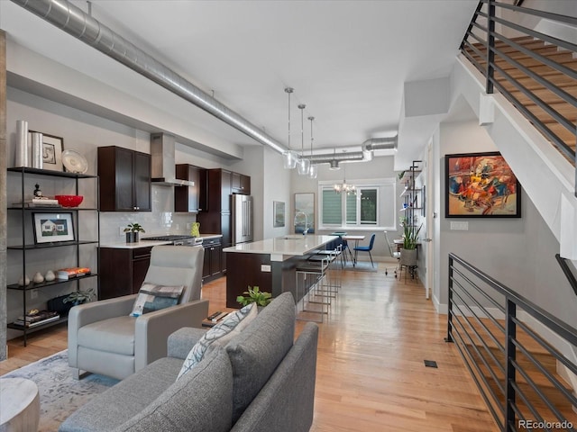 living room featuring light wood-type flooring, stairway, and an inviting chandelier