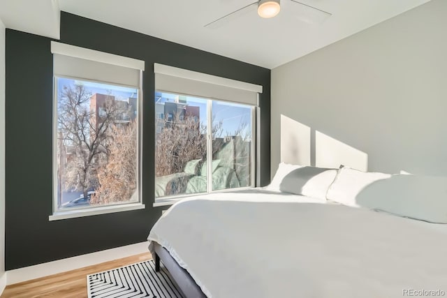 bedroom with ceiling fan, baseboards, and wood finished floors