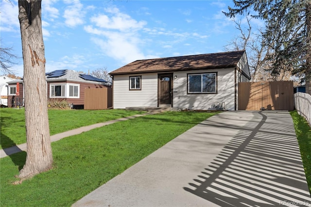 ranch-style home with solar panels and a front lawn