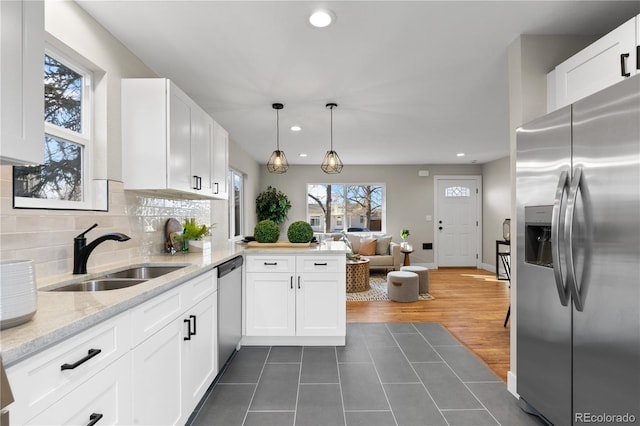 kitchen with appliances with stainless steel finishes, backsplash, sink, decorative light fixtures, and white cabinetry