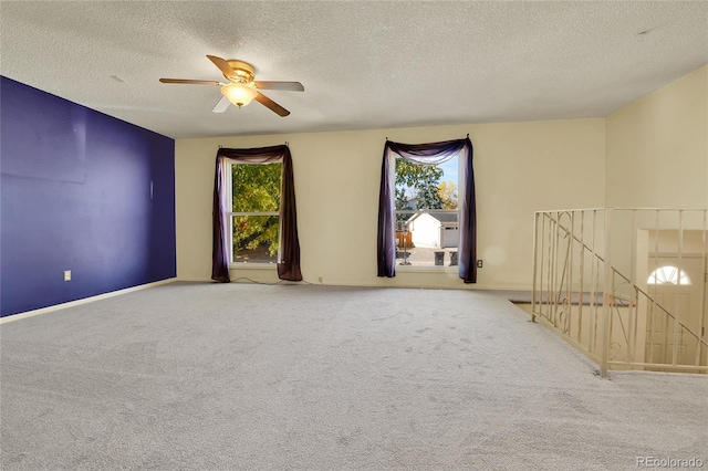 carpeted empty room with ceiling fan and a textured ceiling