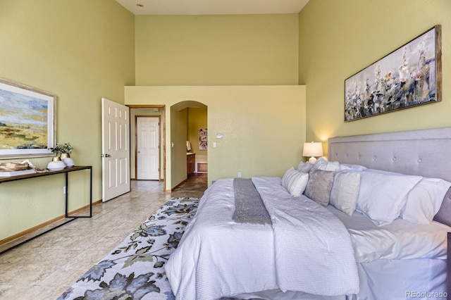 tiled bedroom with arched walkways, baseboards, and a high ceiling