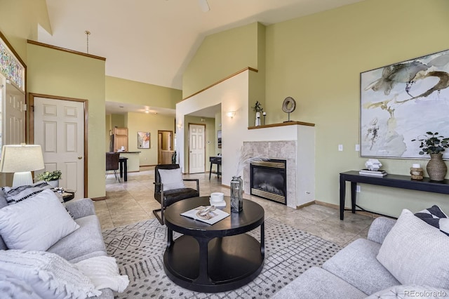 living area featuring light tile patterned floors, high vaulted ceiling, a glass covered fireplace, and baseboards