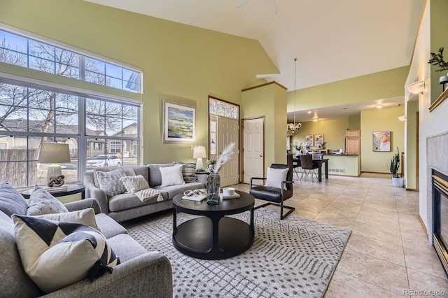 living area featuring baseboards, visible vents, a tiled fireplace, high vaulted ceiling, and light tile patterned flooring