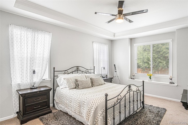 carpeted bedroom with a tray ceiling, ceiling fan, and ornamental molding