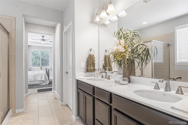 bathroom with tile patterned floors, ceiling fan with notable chandelier, walk in shower, and vanity