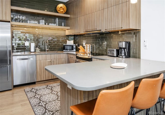 kitchen with a sink, appliances with stainless steel finishes, modern cabinets, and a peninsula