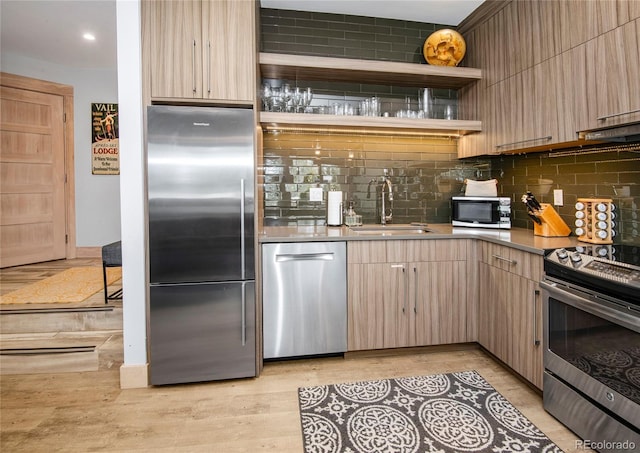 kitchen featuring a sink, light wood-style floors, backsplash, and stainless steel appliances