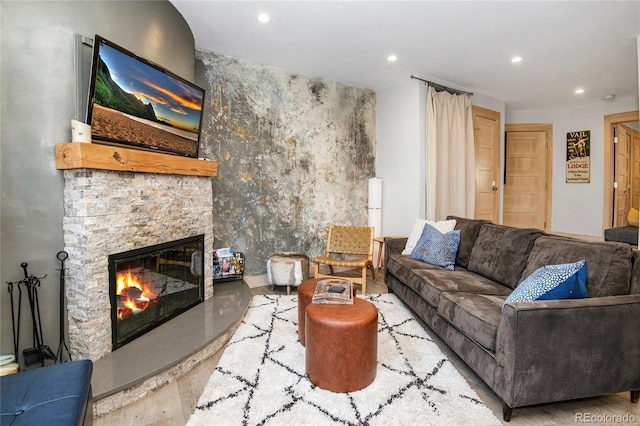 living area featuring a stone fireplace, recessed lighting, and wood finished floors