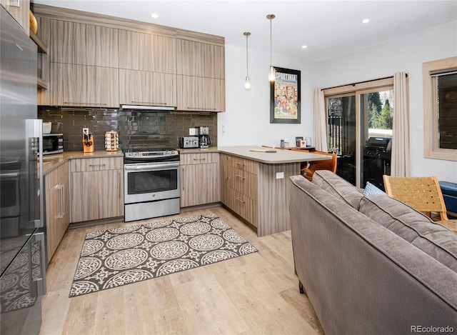 kitchen featuring light countertops, appliances with stainless steel finishes, light wood-type flooring, and a peninsula
