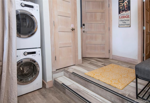 clothes washing area with light wood-style floors, stacked washer and clothes dryer, and laundry area