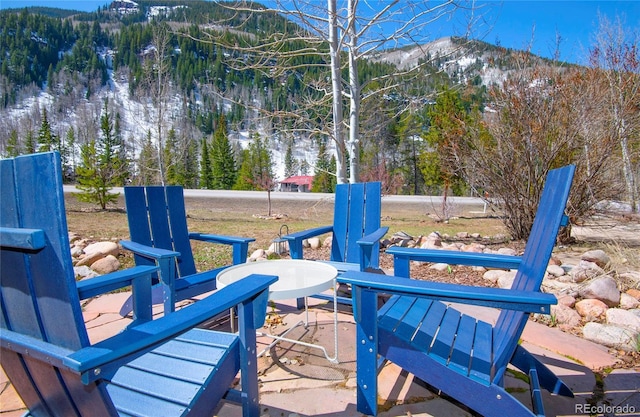 deck with a view of trees, a mountain view, and a patio area