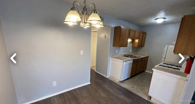 kitchen with a textured ceiling, white appliances, baseboards, light countertops, and dark wood finished floors