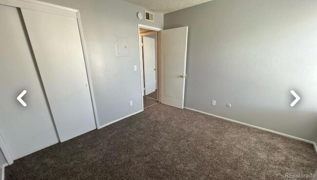 unfurnished bedroom featuring baseboards, visible vents, a textured ceiling, carpet floors, and a closet