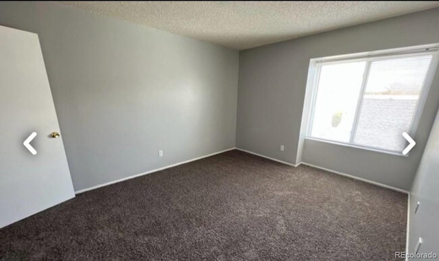 unfurnished room with dark colored carpet, a textured ceiling, and baseboards