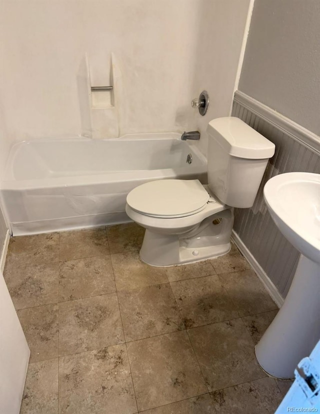 bathroom featuring toilet, shower / tub combination, and wainscoting