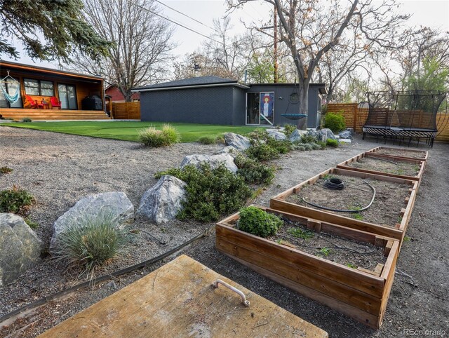 view of yard featuring a trampoline, a garden, and fence
