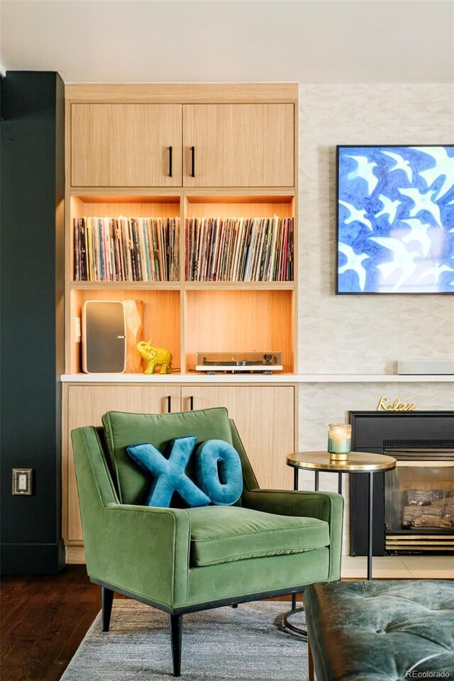 living area with a glass covered fireplace and wood finished floors