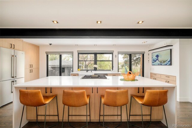 kitchen with modern cabinets, a spacious island, high quality fridge, gas stovetop, and light countertops