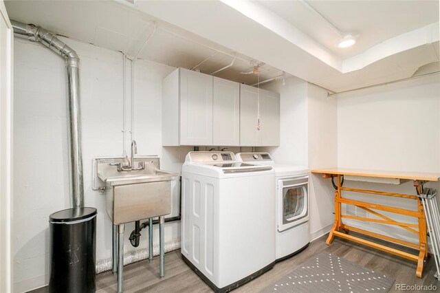 clothes washing area with separate washer and dryer, cabinet space, and light wood finished floors