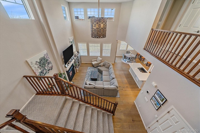 living area with stairway, baseboards, a high ceiling, and hardwood / wood-style floors