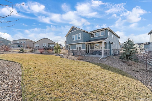 rear view of property with a yard, stone siding, and a residential view