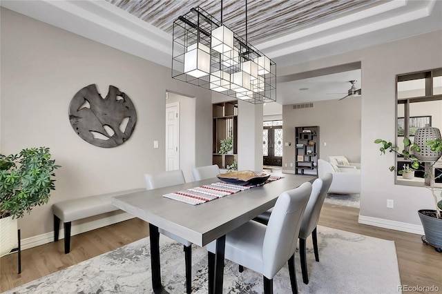 dining room featuring a towering ceiling, french doors, ceiling fan, and hardwood / wood-style flooring