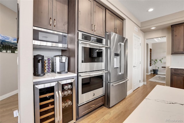 kitchen with wine cooler, light wood-type flooring, stainless steel appliances, and dark brown cabinetry