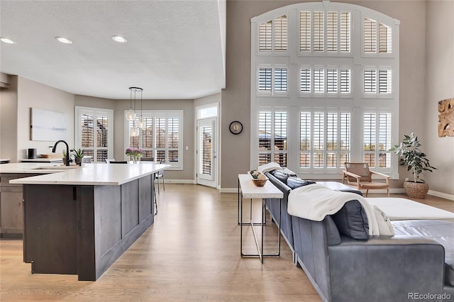 kitchen featuring pendant lighting, sink, a center island, light hardwood / wood-style floors, and a textured ceiling