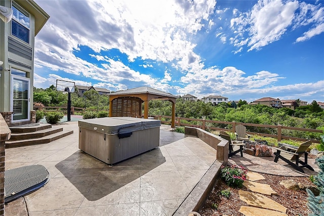 view of patio / terrace featuring a gazebo, a hot tub, and a fire pit