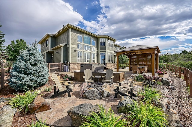 view of patio / terrace featuring a gazebo, a hot tub, and a fire pit