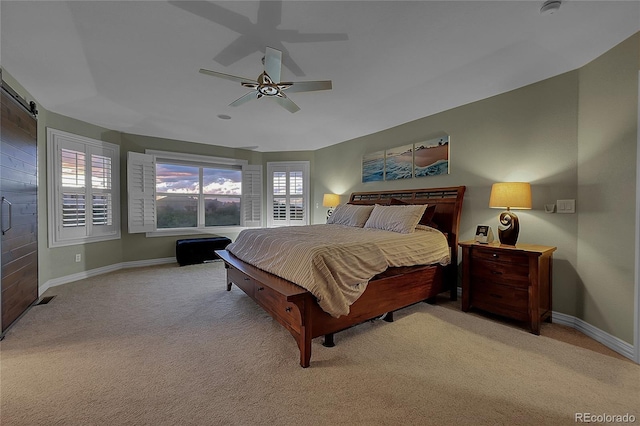 bedroom featuring ceiling fan, a barn door, light carpet, and multiple windows