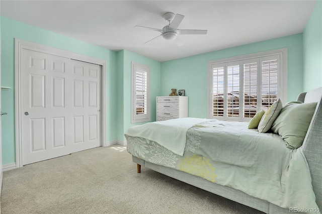 bedroom with light colored carpet, ceiling fan, and a closet