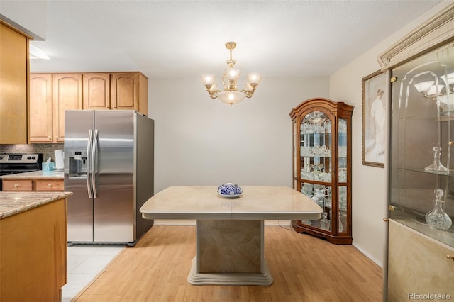 kitchen featuring hanging light fixtures, stainless steel appliances, an inviting chandelier, light hardwood / wood-style flooring, and decorative backsplash