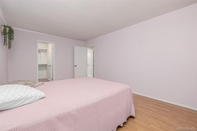 bedroom with a spacious closet, a closet, and light hardwood / wood-style flooring