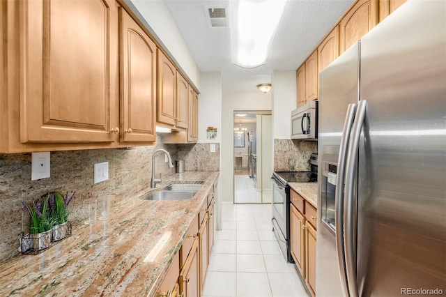 kitchen featuring light stone countertops, light tile patterned floors, sink, and appliances with stainless steel finishes