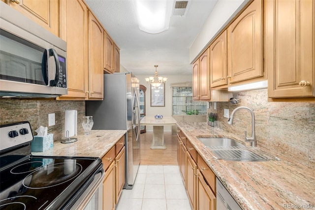 kitchen with light stone countertops, sink, light tile patterned floors, and appliances with stainless steel finishes