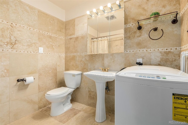 bathroom with tile patterned floors, toilet, tile walls, and washer / clothes dryer