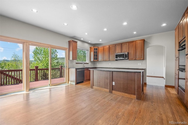 kitchen with stainless steel appliances, recessed lighting, brown cabinets, light wood-style floors, and a kitchen island